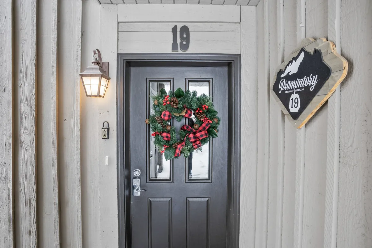 A warmly decorated front door adorned with a wreath and welcoming details, including a house number and lamp. The entrance radiates hospitality and hints at festive gatherings and cozy returns after a day on the slopes.