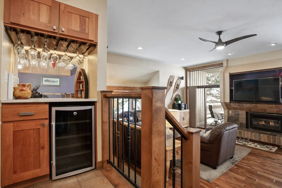 A stylish nook featuring comfortable leather seating, a fireplace, and a counter with hanging wine glasses and a wine cooler beneath. The area exudes a sense of warmth and relaxation, perfect for unwinding with a drink or enjoying social time after a day of adventure.