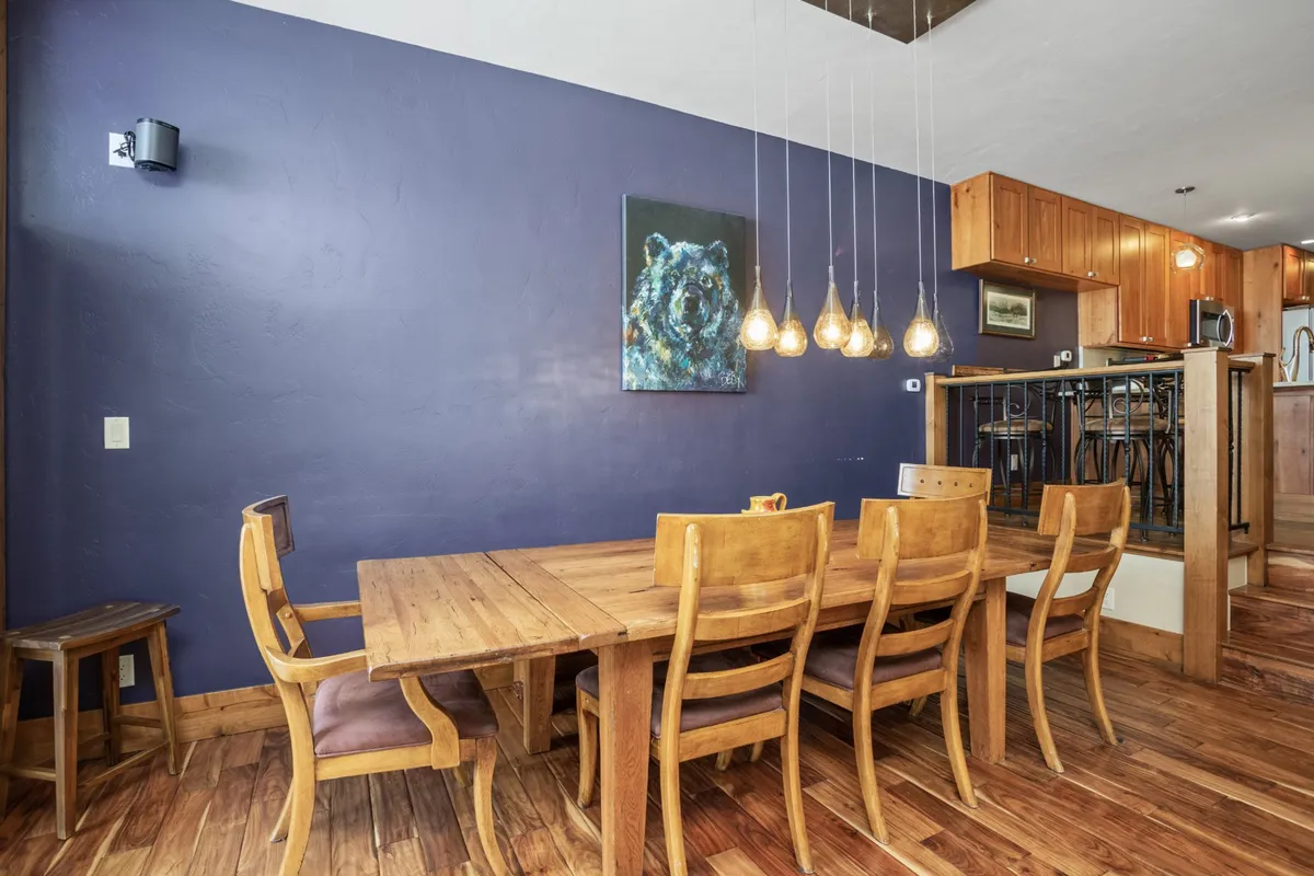 A warm, inviting dining area with a stylish dining table, artistic wall decor, and striking hanging light fixtures. The layout feels both upscale and family-friendly, suited for gatherings or intimate meals.
